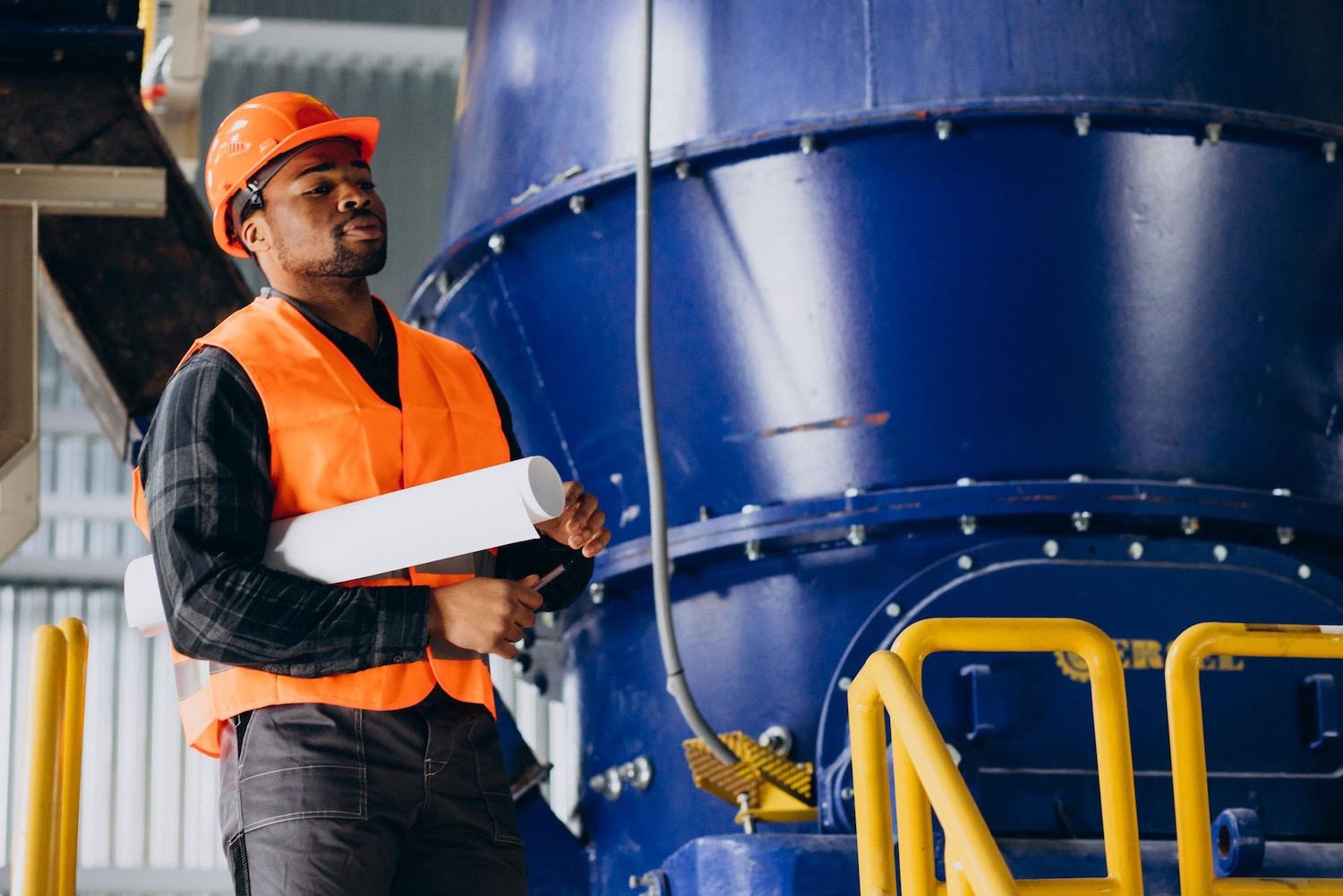 Technician with blueprints beside industrial equipment — Industrial Project Management & Consulting